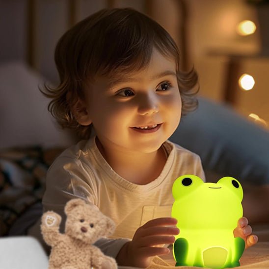 petit garcon heureux touche veilleuse bebe grenouille verte assise